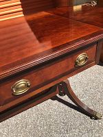 Close-up of one of the desk drawers and brass drawer pulls showing wood grain and hardware detail.