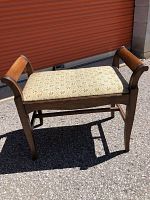 Full view of wooden framed bench with upholstered floral seat taken outdoors.