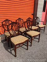 Full view of six Georgian style dining chairs, including one armchair, showing shield backs and patterned upholstery.