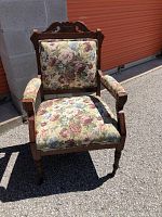 Front view showing floral upholstery on seat, back and armrests with carved wooden frame and turned legs.