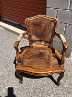 Front view of cane armchair highlighting cane seat and back with curved wooden frame and cushioned arms.