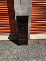 Front view of the tall lingerie chest showing all six drawers and brass knobs; chest has a distressed walnut finish.