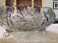 Side view of crystal bowl showing cut glass patterns and rounded feet.