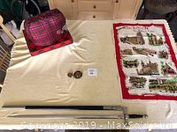 Overview photo showing all items: brooches, sword on tartan cloth, linen towel, and tea cozy