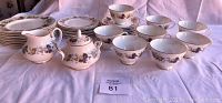 Full set arranged on table showing cups, saucers, plates, creamer, and sugar bowl under natural light.