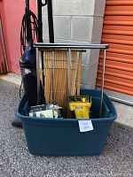 Dirt Devil upright vacuum, clothes rack, wooden baby gate, Eureka handheld vacuum, and McCulloch steam cleaner in a plastic bin outside.