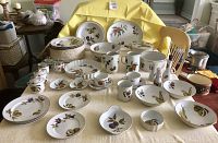 Full spread of porcelain plates, bowls, cups and serving dishes arranged on table