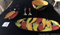 Photo of the large salad bowl, serving fork and spoon, and elongated platter on black tablecloth showing chili pepper designs