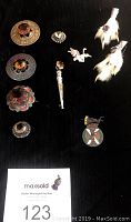 Photo showing 7 pieces: 4 silver brooches with large faceted stones, 2 silver grouse foot brooches (one with purple stone and fur), and 1 bronze Scottish Highland Dancing medal.