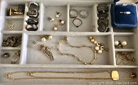 Top-down view of assortment of rings, earrings, necklaces, and bracelets organized in a compartmentalized jewelry case.