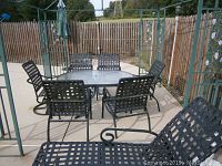 Full view of the patio set outdoors showing table, six chairs, and lounger in fenced yard
