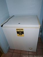 Front view of white chest freezer with EnergyGuide label and power cord on top.