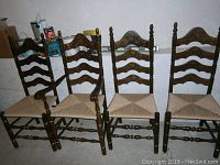 Full view showing all four dark walnut farmhouse dining chairs in a row, three armless and one with arms, with woven rush seats and ladder back design.