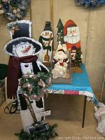 Photo showing the 4 ft snowman in front with wreath and scarf, standing next to the sleigh with lace Santa, wooden snowman with broom, and Christmas tree in the background