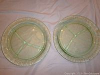 Two green depression glass plates with three-section grill dividers viewed from above.