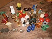 Overview photo showing all 20 salt and pepper shaker sets with various quirky Mid-Century Modern designs including fruit, characters, bottles, lamps, and more.