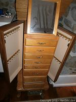 Front view of tall oak jewelry box with side doors open showing hooks and top mirror