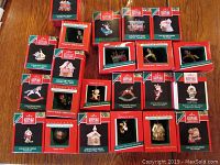 Photo showing 24 miniature Hallmark Keepsake ornaments in original red and green packaging, displayed on a wooden surface.