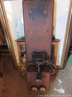 Full view of vintage wooden wall telephone with black metal box and metal bells at base.