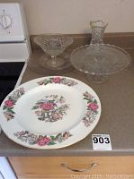 Large Cathay Wedgwood floral plate, cut glass cake plate, candy dish, and small cut glass vase on kitchen counter.