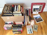 Photo showing two boxes and stacks of books with a variety of classic and literary titles.