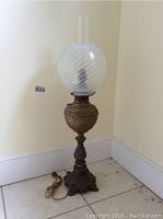 Full view of 31-inch decorative lamp with swirl glass shade and chimney on tall ornate metal base.