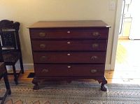 Front view of the four drawer chest showing the intact drawers with lion head knobs, keyholes, and claw and ball feet.