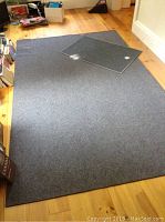 Large blue rectangular rug laid on wooden floor with a small glass panel on top