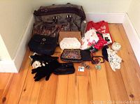 Full overview of ladies accessories lot including various handbags, gloves, scarves, and jewelry items arranged on wood floor.