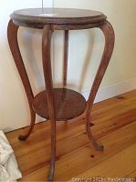 Full view of wooden round plant stand with curved legs