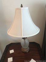 Full lamp with glass base and white shade shown from front view