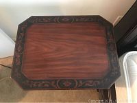 Top-down view of side table showing wooden surface with dark floral inset edge