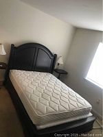 View of the queen size bed with headboard, mattress, and side tables with lamps on each side.