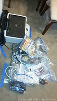 Dell V313W printer shown with various items including batteries and wires in plastic bags on floor.