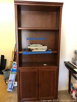 Front view of cherry stained wooden bookcase showing open shelves and two-door cabinet below.