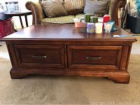 Front view of cherry stained wooden coffee table showing two large drawers with braided style metal pulls.