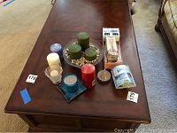 Image showing all candles, glass holders, and air freshener items arranged on a dark wood coffee table.