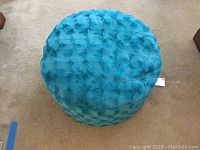 Top view of plush blue ottoman showing textured swirl pattern fabric