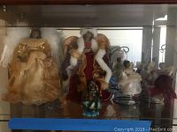 Photo of two large angel Christmas tree toppers with gold and red dresses and one standing figurine in green.