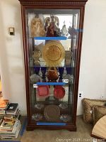 Front view of curio cabinet with various shelves containing angel figurines, glassware, decorative plates, and other ornaments.