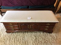 Front view of cedar chest showing drawers and cabinet doors with upholstered top