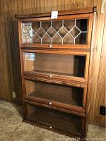 Front view of oak lawyer bookcase showing four glass front doors and decorative leaded glass top door.