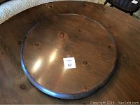 Solid hardwood Lazy Susan on wooden table with 26 inch diameter and custom fitted felt backed protective cover shown partially underneath it.