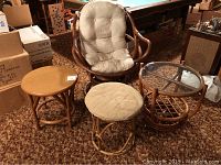 Photo of the full set showing rattan chair with beige cushion, rattan ottoman with beige cushion, glass top rattan side table, and wood top round side table