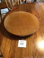 Top and side views of a 16 inch round lazy Susan with wood grain finish placed on a wooden table.