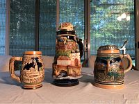 Front view of three steins placed side by side showing shape, size, and design color differences