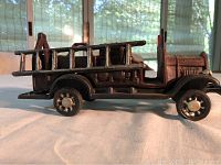 Side profile showing the left side of the fire truck with ladder attached and detailing on wheels and body.