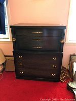 Front view of the black 4 drawer chest showing brass handles and drawers closed