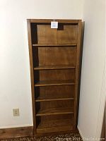 Front view of oak bookcase showing five shelves and the rectangular frame.