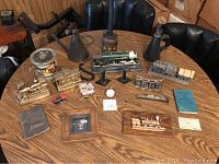 Wide shot of all 22 train memorabilia items arranged on a wooden table showing trains, oilers, phone, books, and collectibles
